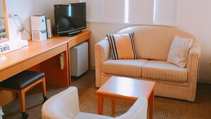 A living room with a sofa, a small table, a television, and a desk with a computer and printer. - Central Hotel Imari (Imari)