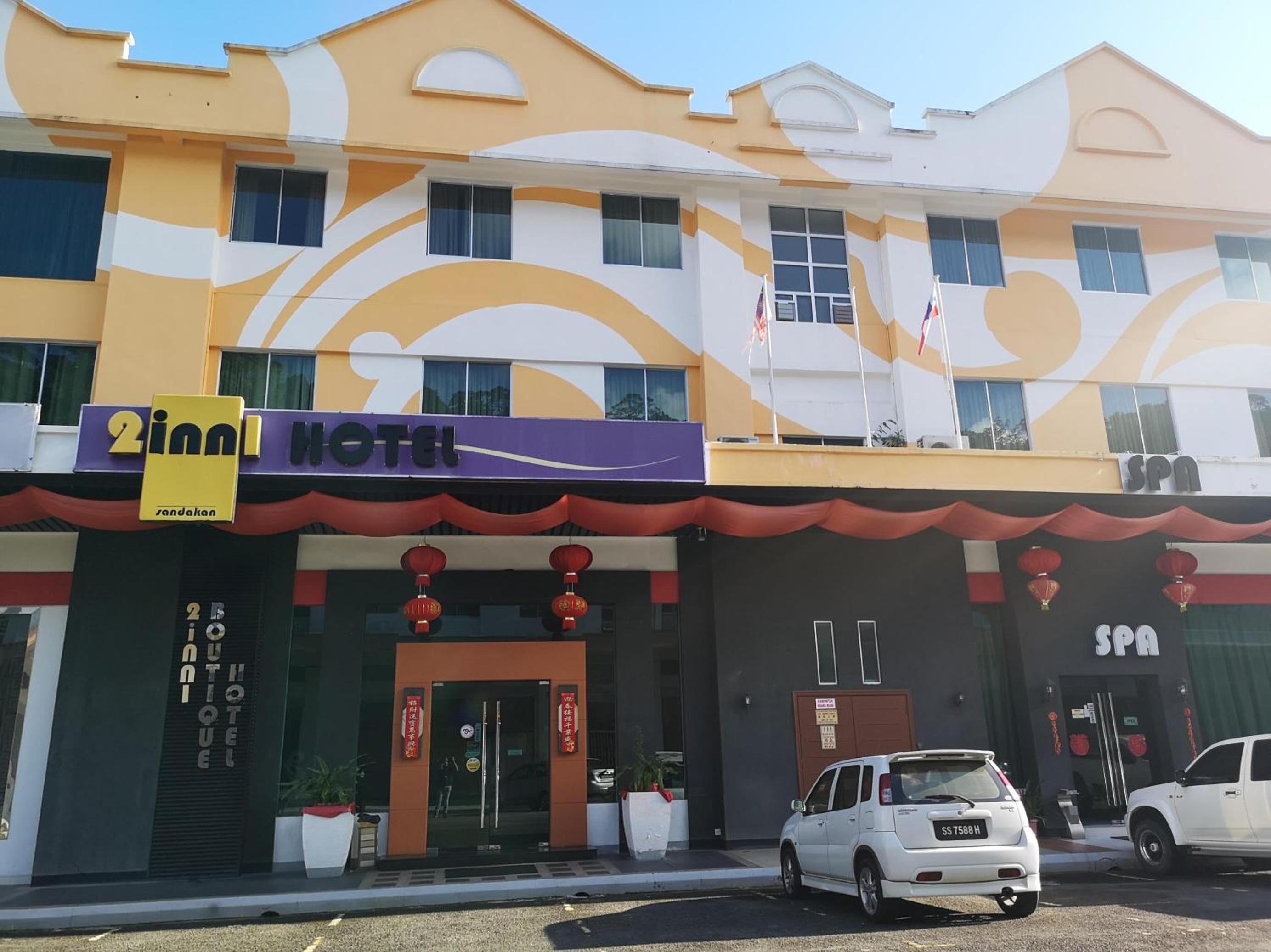 A hotel with a modern facade, a spa, and a parking area with cars.