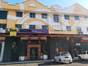 A hotel with a modern facade, a spa, and a parking area with cars.