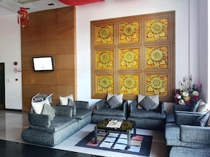 Un hall d’entrée moderne avec des canapés gris, une table basse et une grande œuvre d’art murale représentant des motifs floraux.