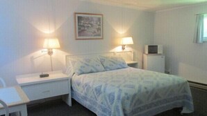 A hotel room with a bed, two bedside tables, a desk, a chair, a TV, and a painting on the wall. - Country Squire Motel (Littleton)