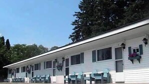 A motel with a row of rooms, each with a window and a small porch area. - Country Squire Motel (Littleton)