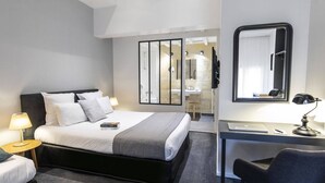 Una habitación de hotel moderna con una cama grande, mesitas de noche con lámparas, un escritorio con silla y un espejo.
