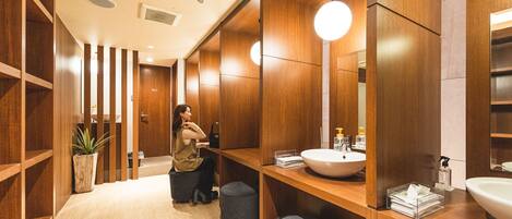 A modern bathroom with wooden paneling, a round mirror, and a white sink.
