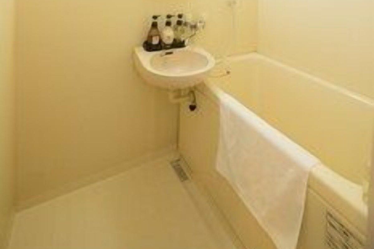 A small bathroom with a sink, a mirror, and a bathtub.