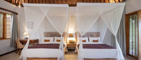 A room with two beds, each with a canopy, a wooden headboard, and a nightstand with a lamp.