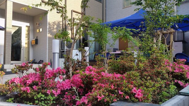 A modern building with a brick facade, large windows, and a covered outdoor seating area. - Tokyo Guest House 2020 (Tokyo)