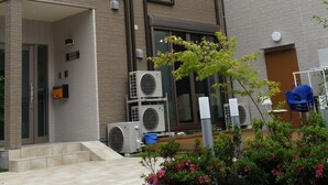 A multi-story building with a brick facade, large windows, and outdoor air conditioning units. - Tokyo Guest House 2020 (Tokyo)
