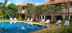 Una piscina al aire libre, sombrillas, sillones reclinables de piscina