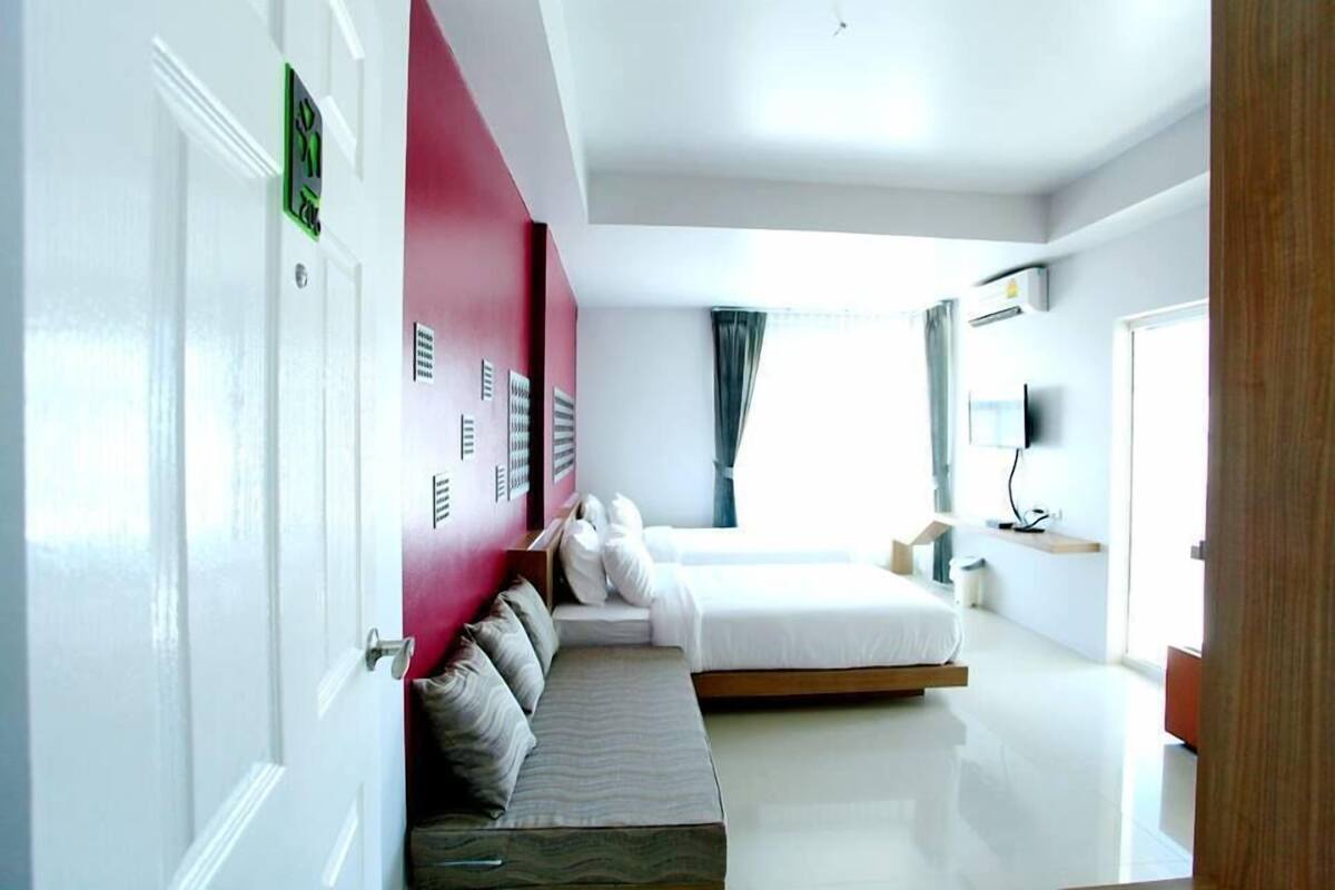 A modern hotel room with a bed, a seating area, and a TV.