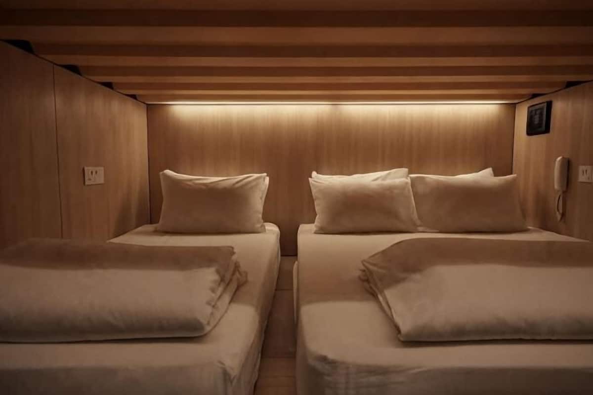 A cabin with two beds, wooden paneling, a phone, and a light fixture.
