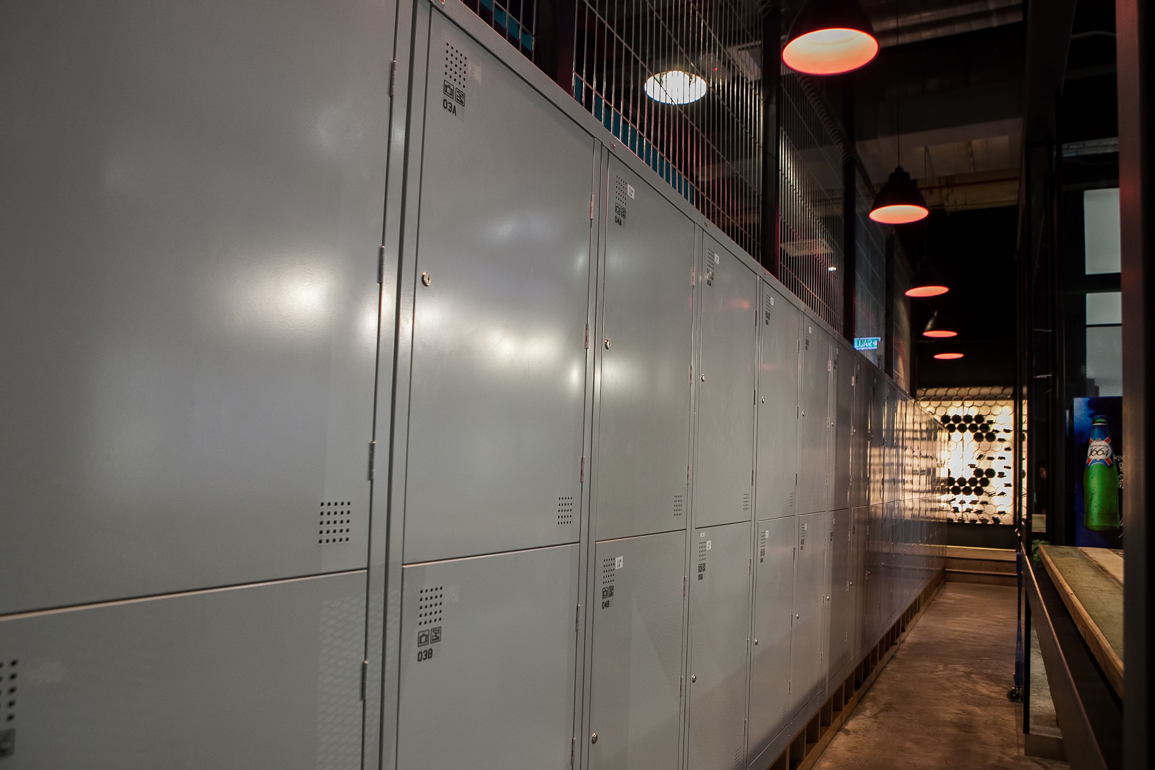 A corridor with metal lockers, a staircase, and a wall with a wine rack.