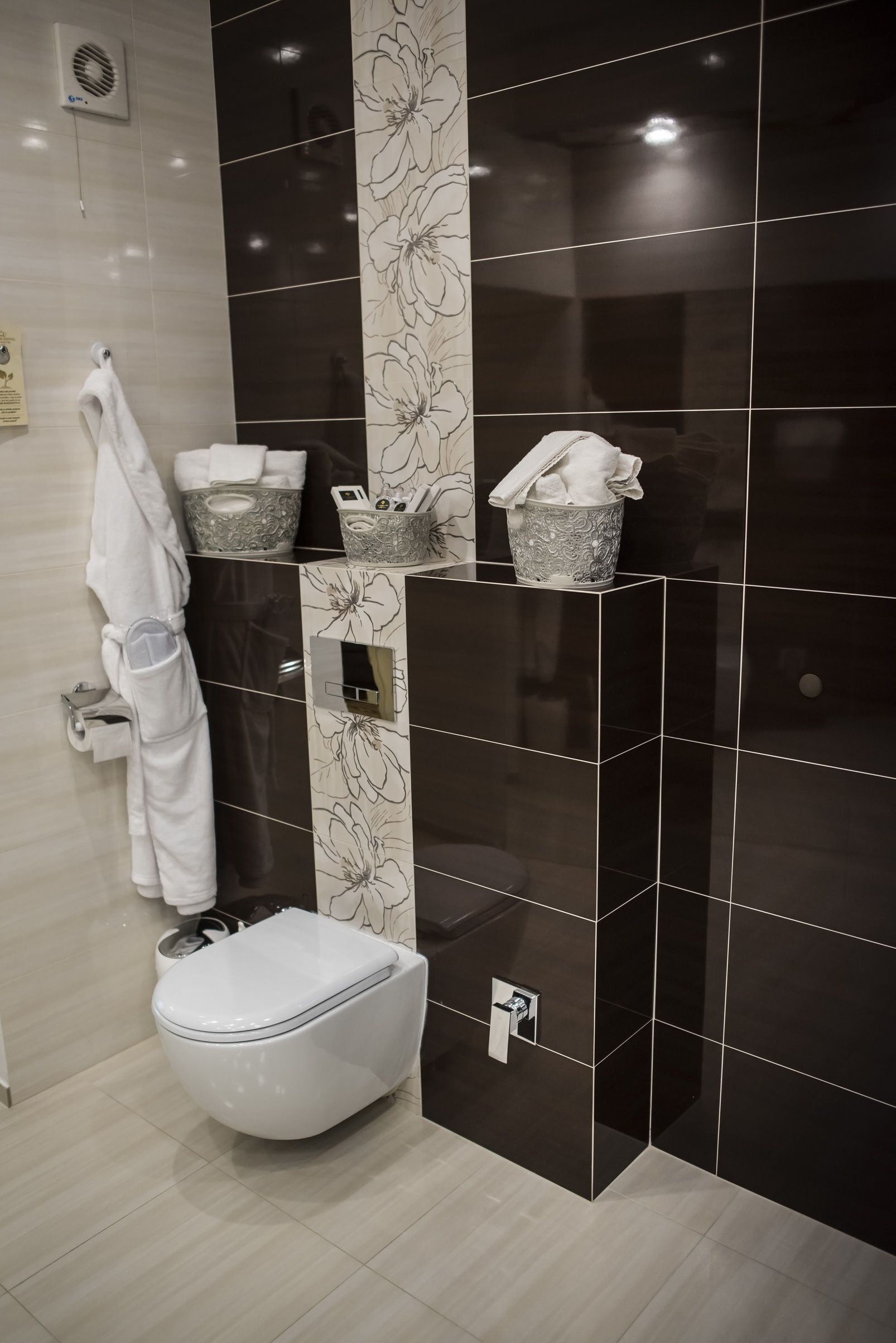 Ein modernes Badezimmer mit Toilette, Handtuchhalter und einer Wand mit floralem Dekor.