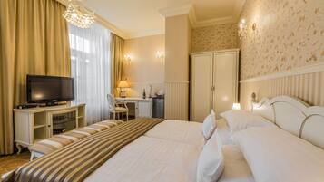 A hotel room with a large bed, a desk with a chair, a television, and a wardrobe.