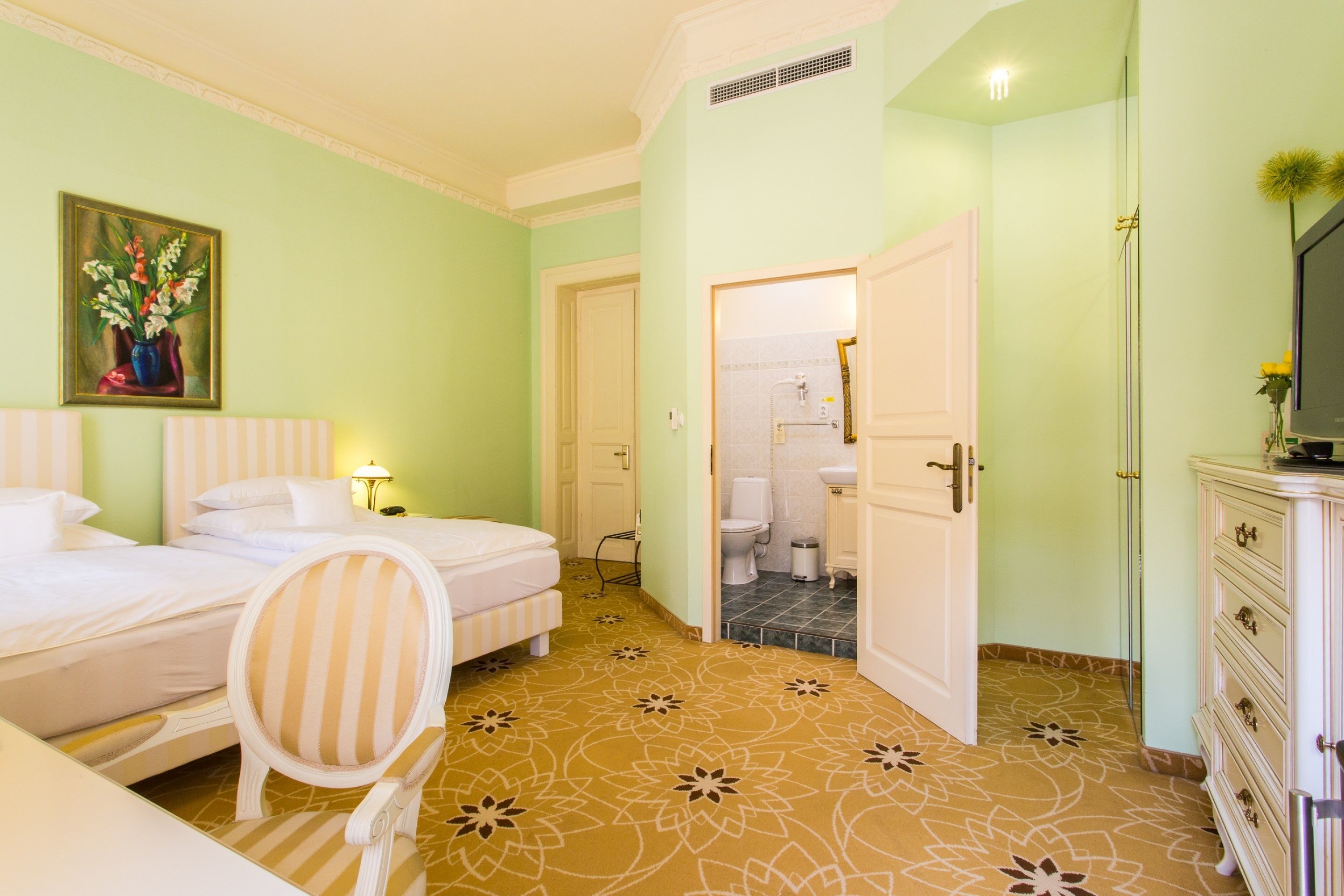 Une chambre d’hôtel avec un lit, une chaise, une commode et un téléviseur.
