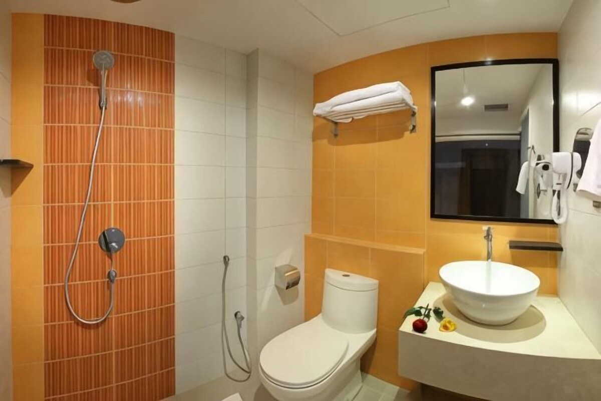 A bathroom with a shower, toilet, sink, and mirror.