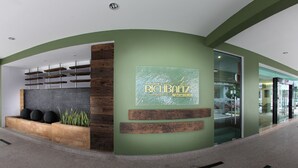A modern hotel entrance with a green facade, a reception desk, and a glass door leading inside. - Hotel Richbaliz (Batu Caves)
