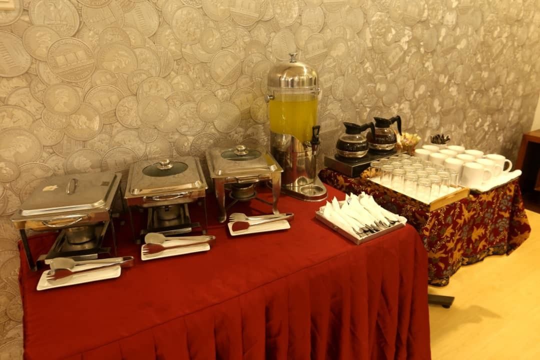 A buffet setup with various food stations, including a coffee machine and a fruit punch dispenser.