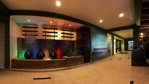 A hotel lobby with a reception desk, a wall-mounted light fixture, and a planter with plants. - Hotel Richbaliz (Batu Caves)