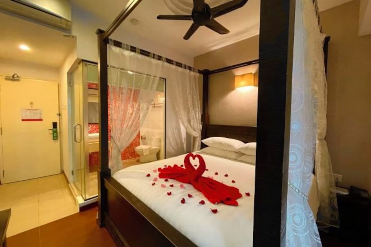 A four-poster bed with a canopy, a ceiling fan, and a shower area visible through a glass door.