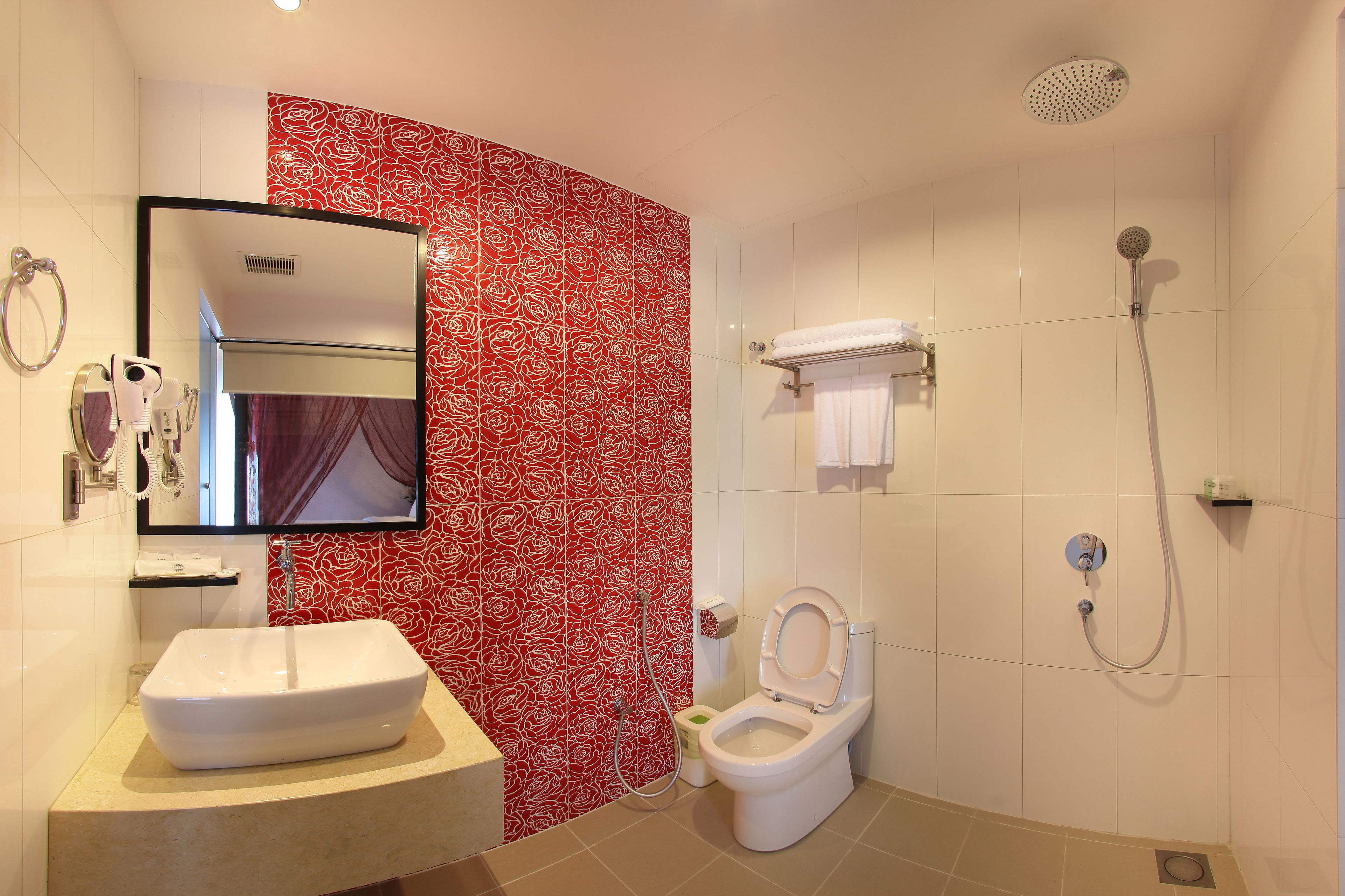 A bathroom with a white sink, a toilet, a shower, and a mirror.