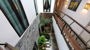 A modern interior with a marble staircase, a small indoor garden, and a wooden railing. - Hotel Richbaliz (Batu Caves)