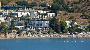 Un hotel en la costa con varias construcciones, sombrillas de playa y vistas despejadas al mar.