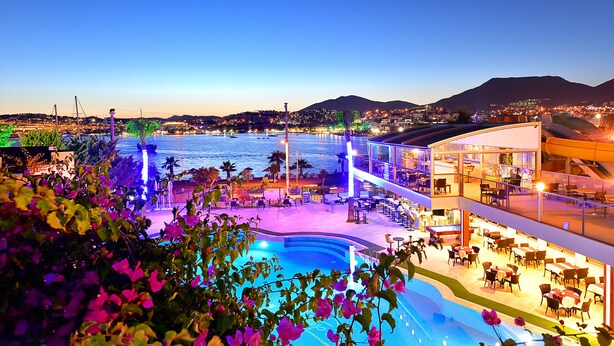Un hotel con piscina, mobiliario exterior y vistas al mar.