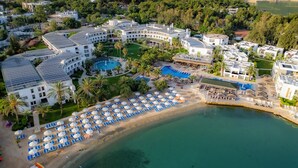 An aerial view of a resort with multiple buildings, a swimming pool, and a beach area with sun loungers and umbrellas. - Samara Hotel Bodrum Ultra All Inclusive (Bodrum)