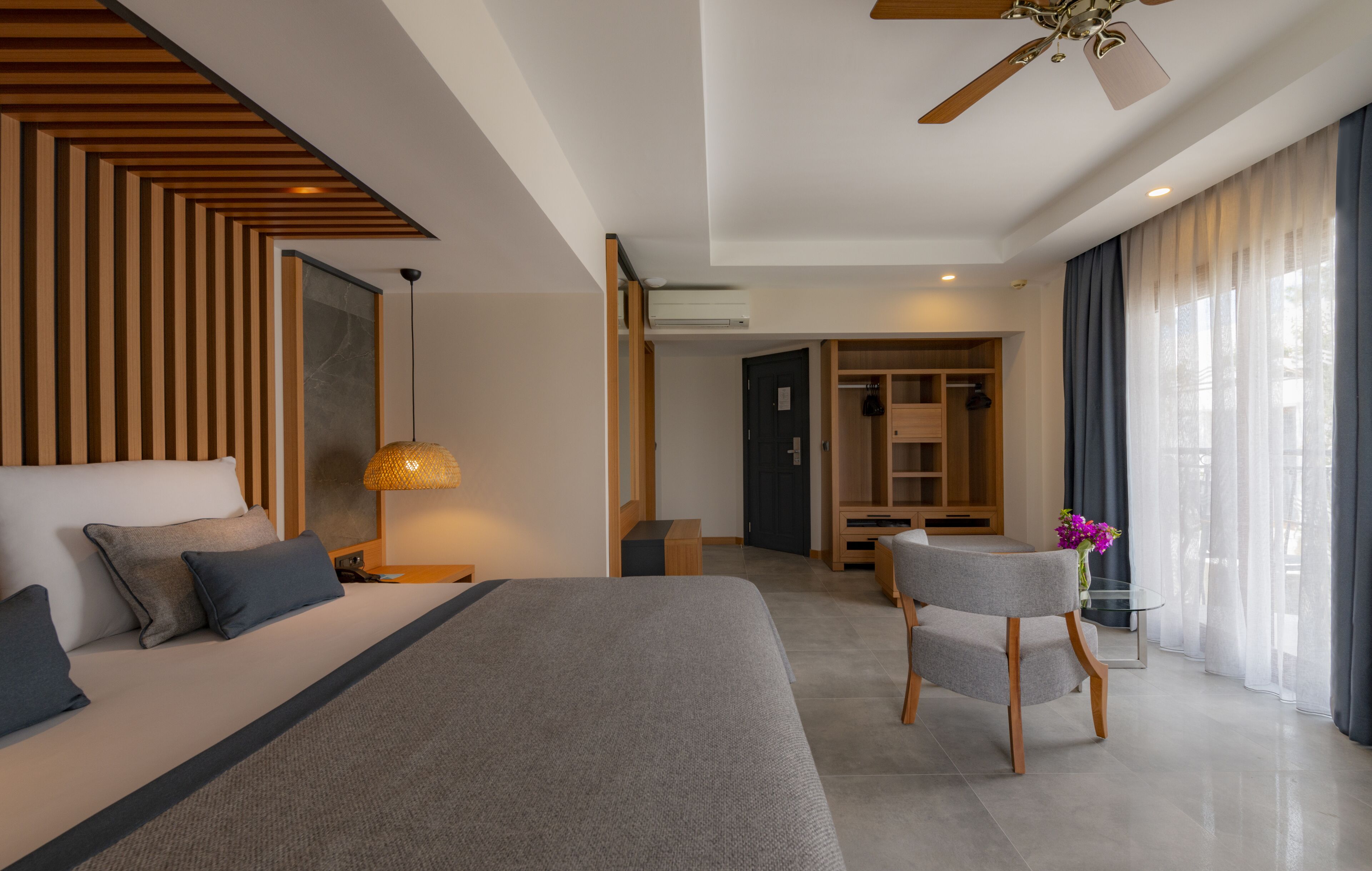 Et moderne hotelværelse med en stor seng, et skrivebord og en stol. Der er et garderobeskab og et badeværelse at se i baggrunden.