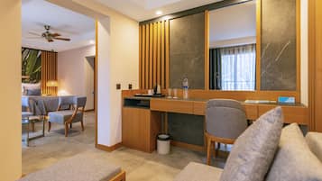 Una habitación de hotel moderna con un escritorio de madera, un sofá cómodo, una zona de comedor y un espejo grande.