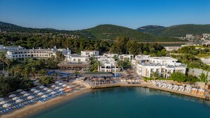 A coastal resort with multiple buildings, a marina, and a beach area with sun loungers and umbrellas. - Samara Hotel Bodrum Ultra All Inclusive (Bodrum)
