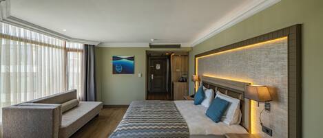 A hotel room with a bed, a sofa, a desk, and a view of the outdoors.