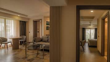 Una habitación de hotel moderna con un sofá, sillones, una mesa de centro de vidrio y vistas al exterior.