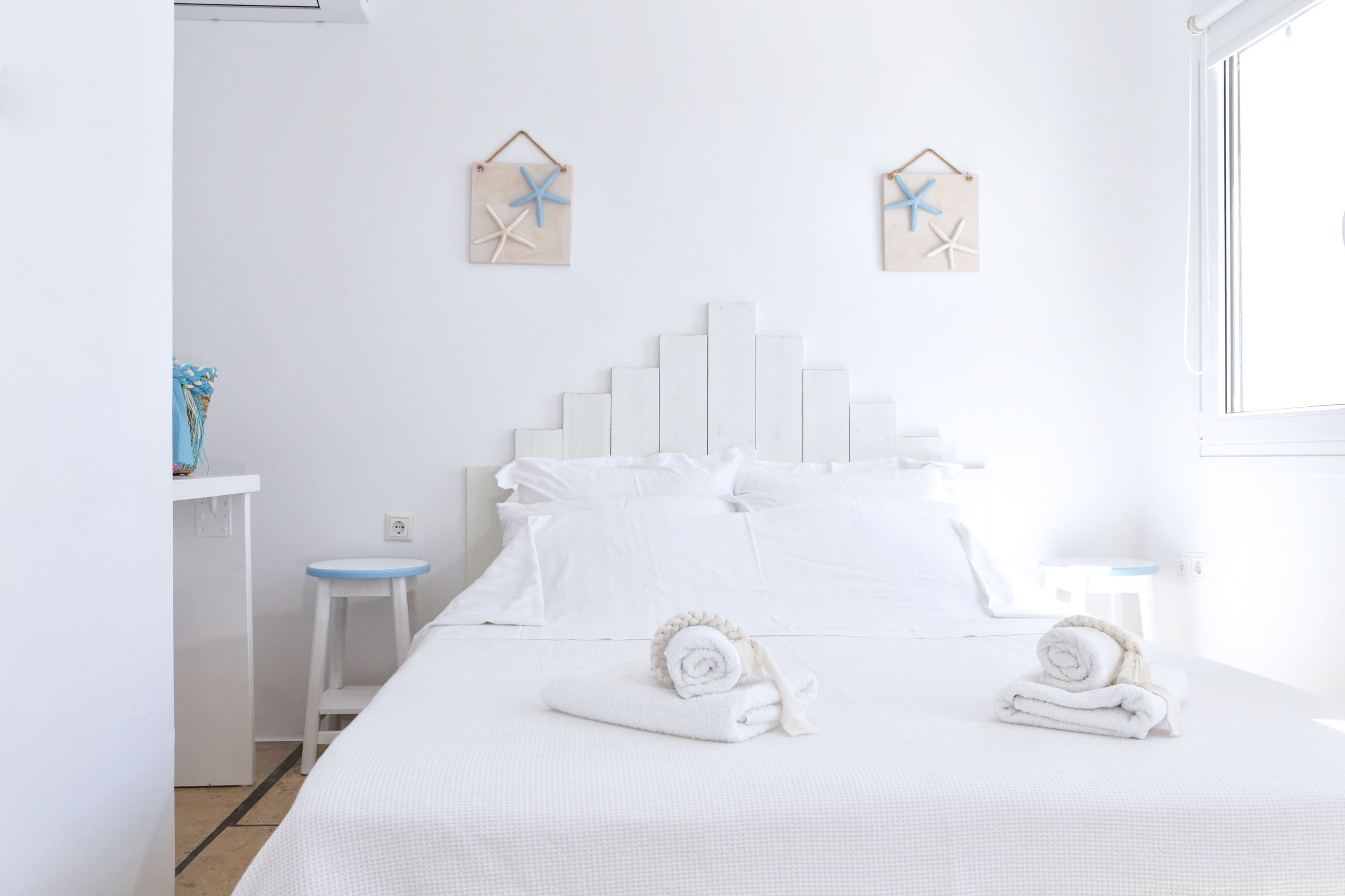 A white bedroom with a bed, two nightstands, and wall decorations.
