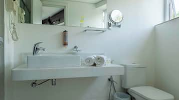 A modern bathroom with a white sink, mirror, and toilet.