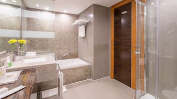 A modern bathroom with two sinks, a bathtub, and a glass shower enclosure.