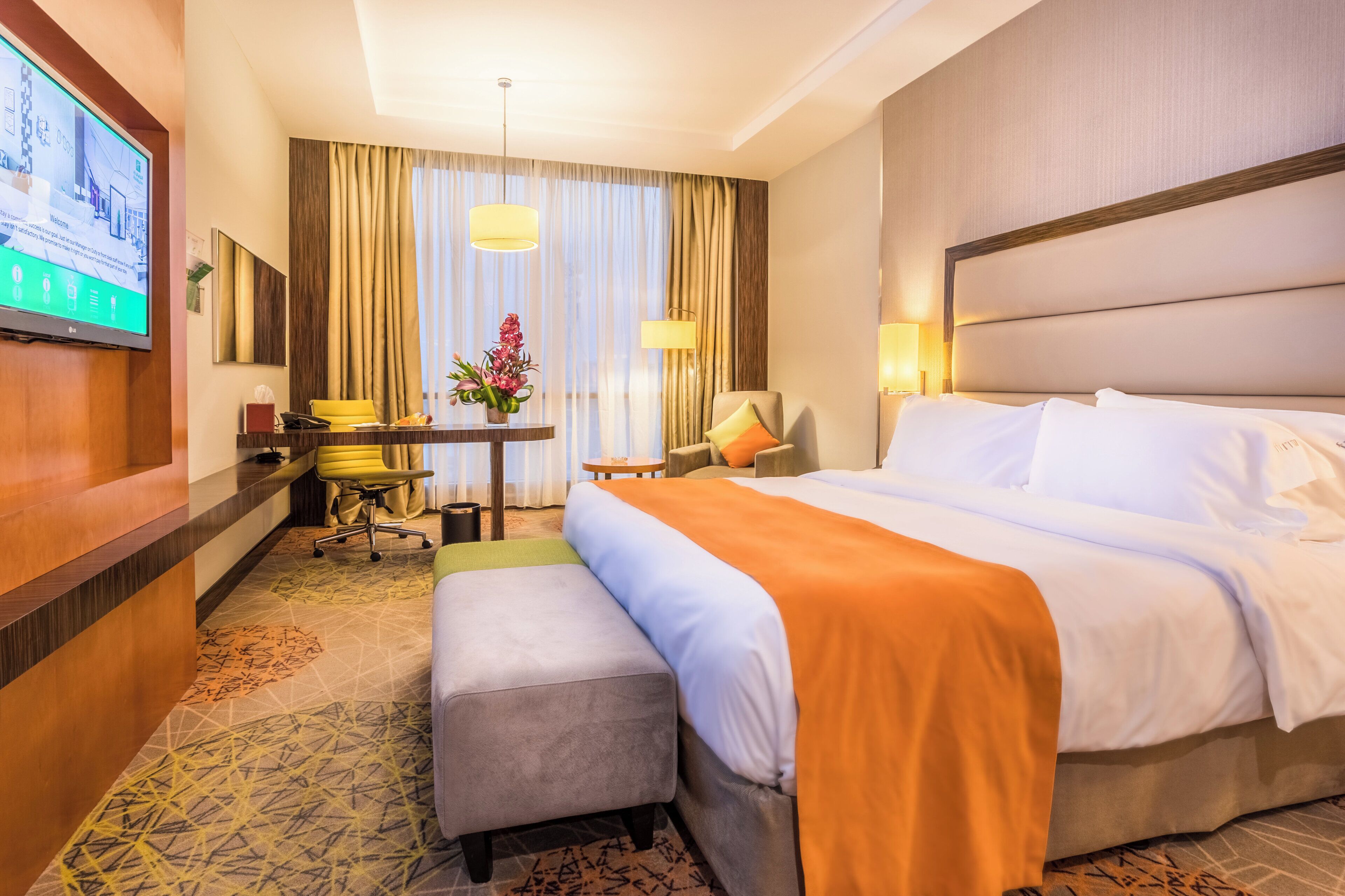 A hotel room with a bed, desk, chair, and television.