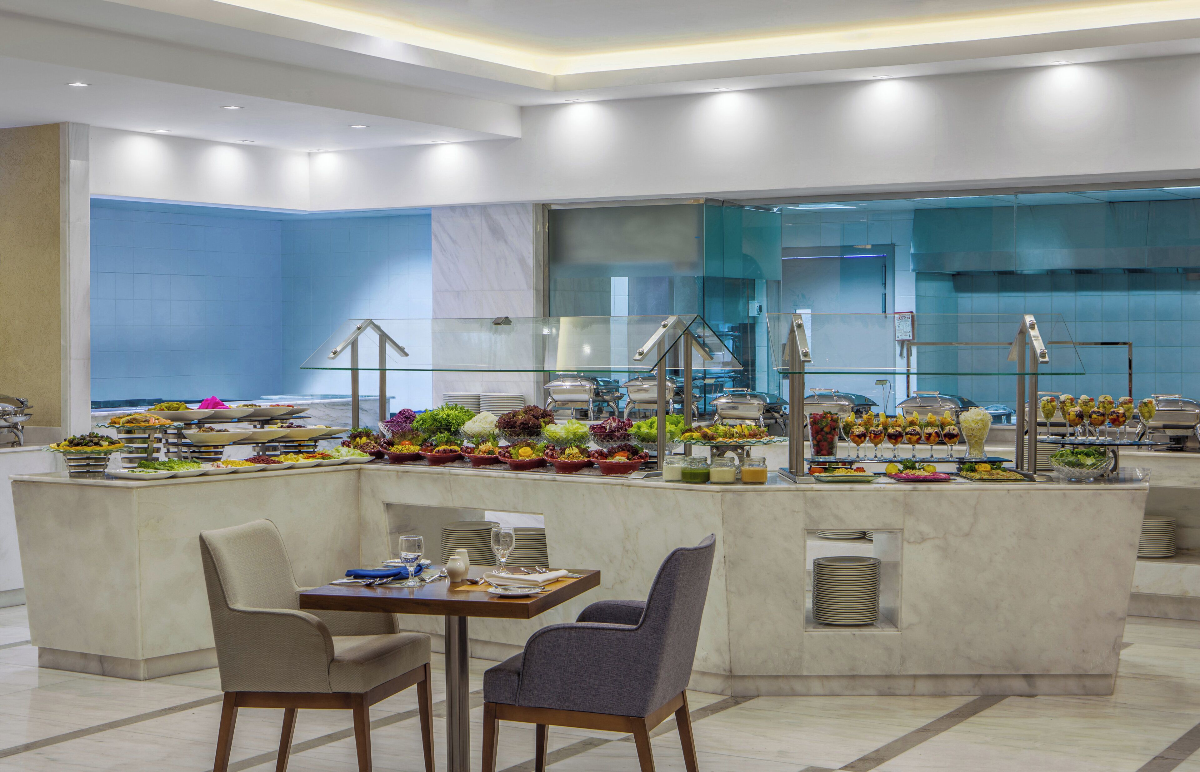 A modern buffet setup with a variety of food items and a seating area with two chairs.