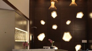 A modern reception area with a marble reception desk, geometric wall lighting, and a clean, contemporary design.