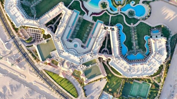 An aerial view of a resort with multiple swimming pools, a beach, and a pier. - Baron Palace Sahl Hasheesh (Sahl Hasheeh)