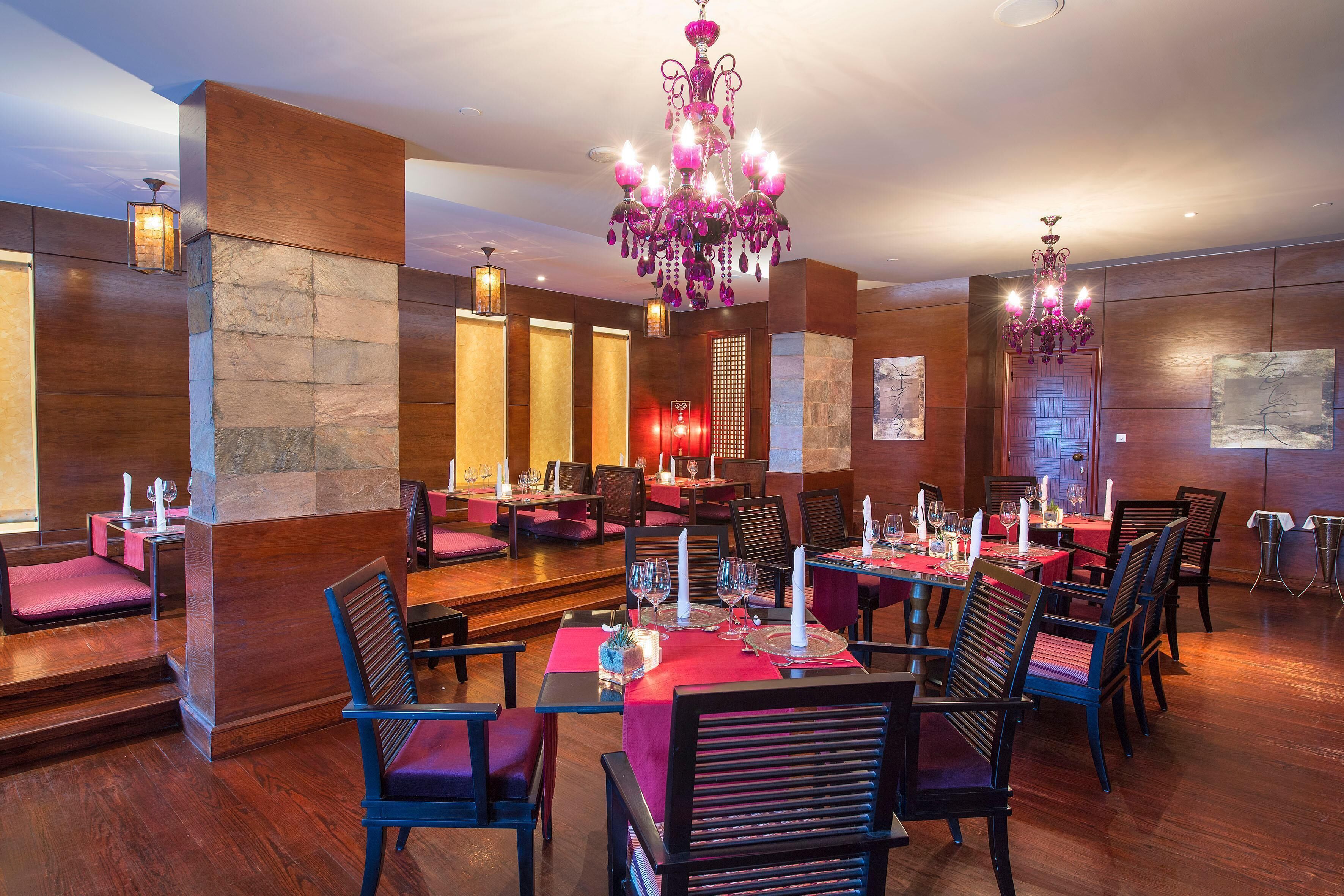 Un ristorante con pareti in legno intarsiato, un lampadario e tavoli apparecchiati per la cena.