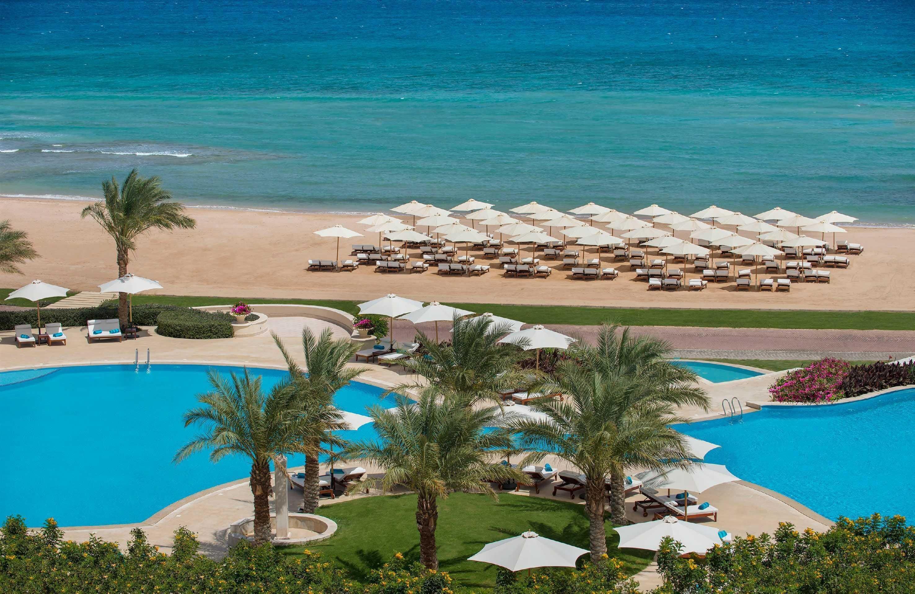 Un resort con múltiples piscinas, zonas de descanso frente a la playa y vistas al océano.