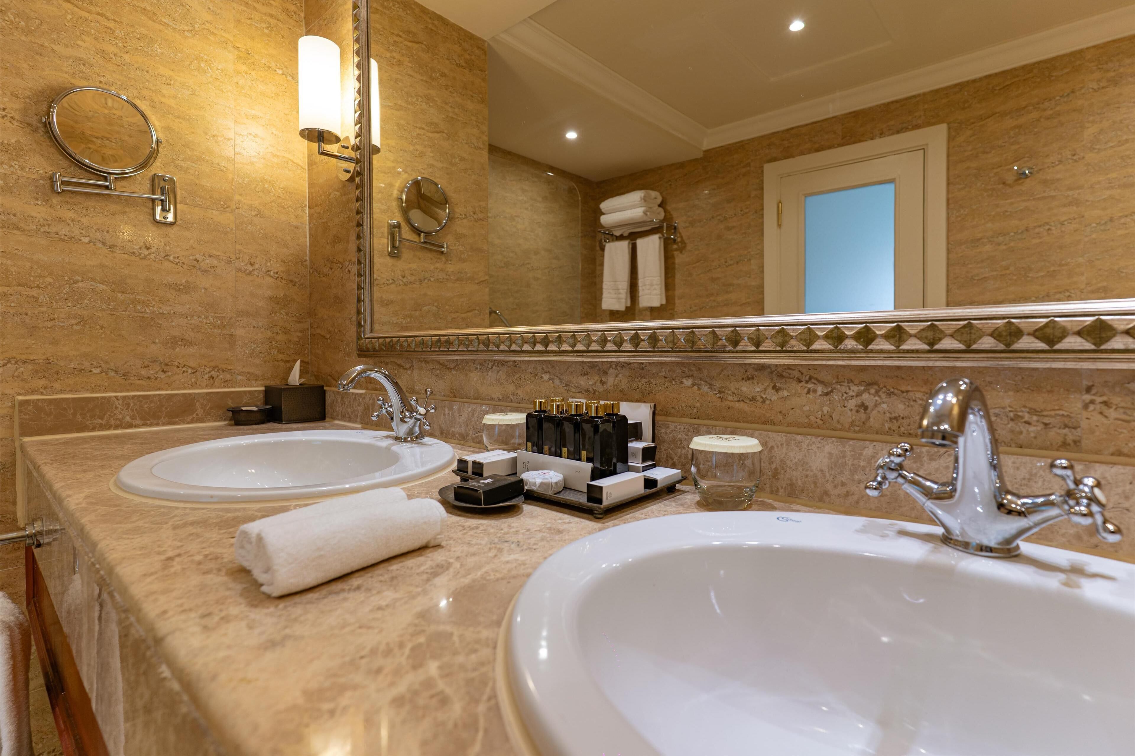 A bathroom with two sinks, a large mirror, and a towel rack.