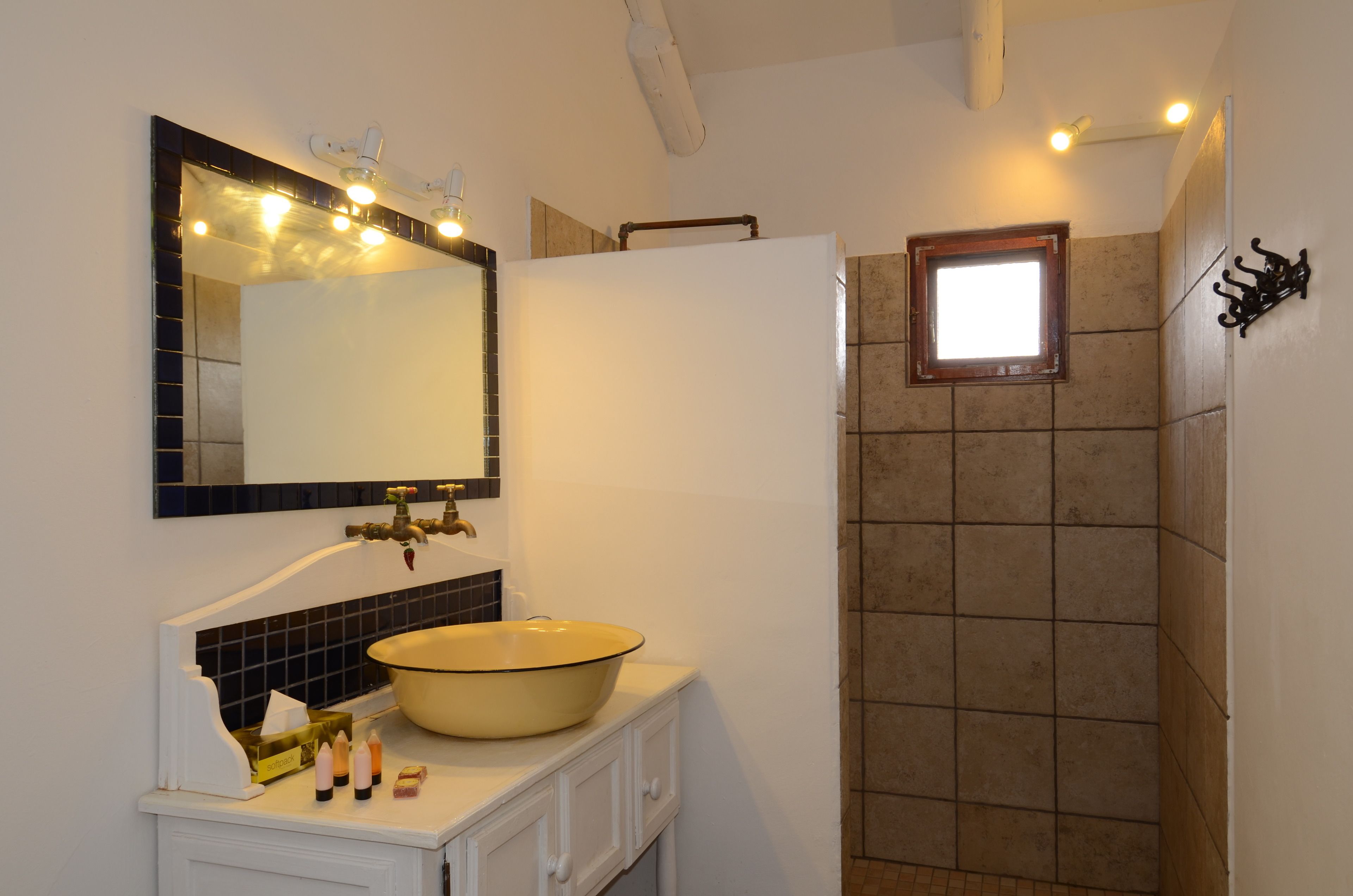 Un baño con lavamanos amplio, espejo y zona de ducha.
