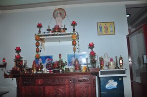 A room with a wooden cabinet, a Samsung refrigerator, and various decorative items including statues and framed pictures. - Homestay Countryside (Da Nang)