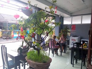 Un espace de détente intérieur avec un grand arbre en pot, des chaises et des tables.