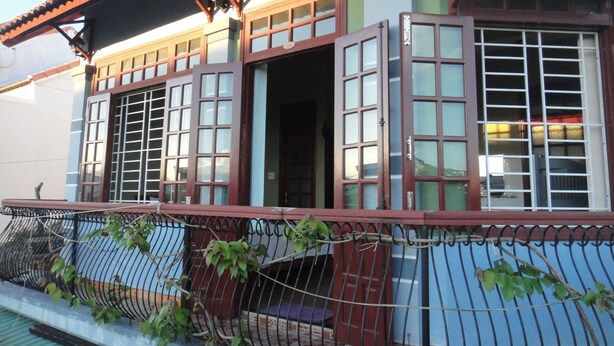 A building with multiple windows, a balcony with a metal railing, and a door. - Homestay Countryside (Da Nang)