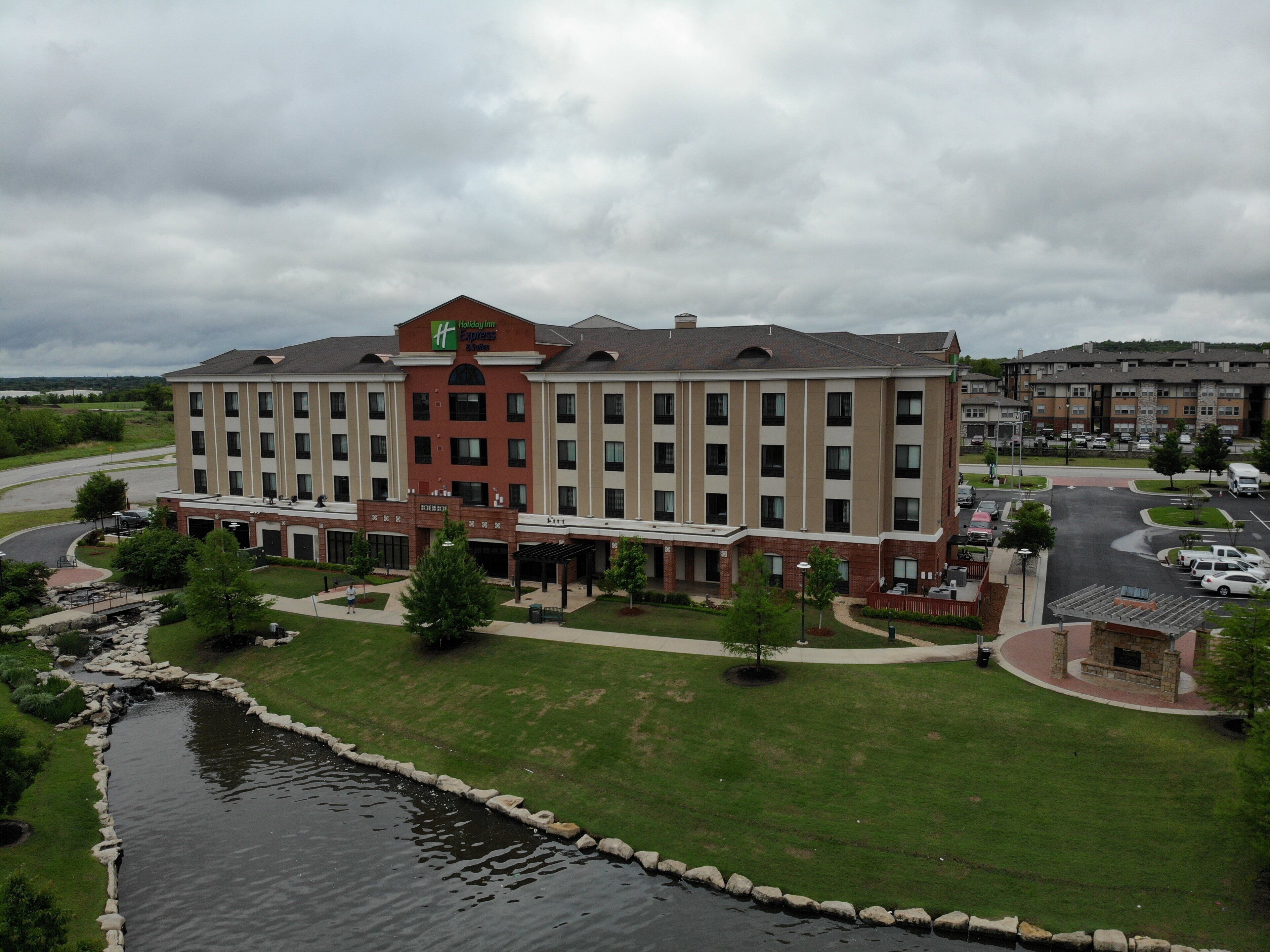 A large hotel with multiple floors, a parking lot, and a small water feature.