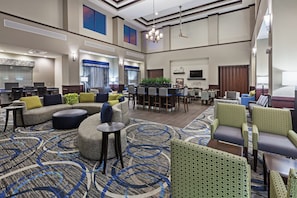 A spacious hotel lobby with a seating area, a reception desk, and a large screen. - Holiday Inn Express & Suites Glenpool-Tulsa South by IHG (Glenpool)